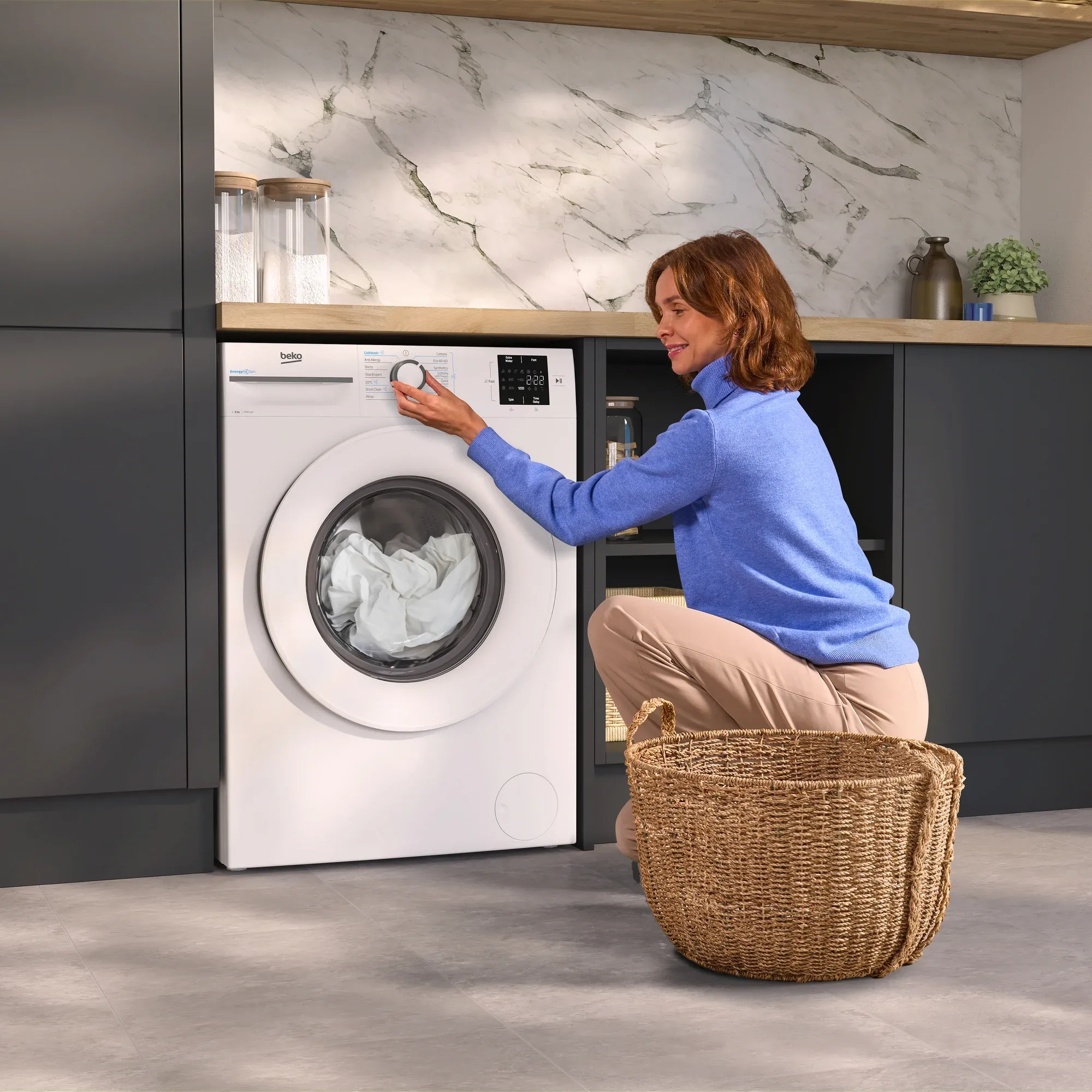Woman turning dial on white Beko washing machine
