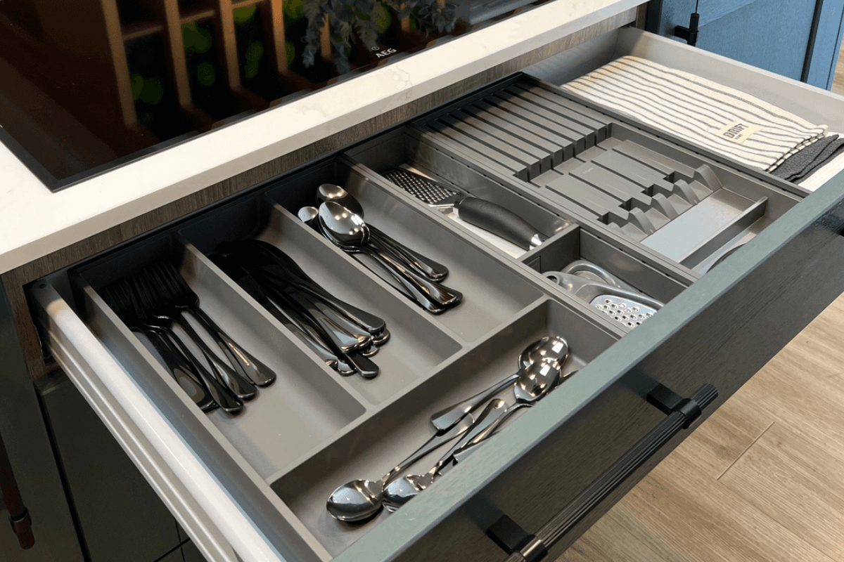 Kitchen with open drawer showing cutlery in tray and tea towels